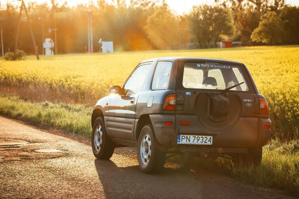 Toyota RAV4 parked by a sunny rural road with fields and trees in the background. Best Dash Cam for Toyota RAV4
