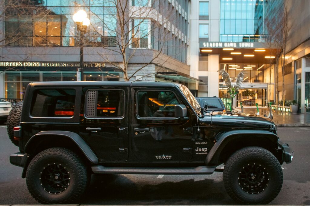 A black jeep sits in front of a building. Best Camper Shell for Jeep Gladiator